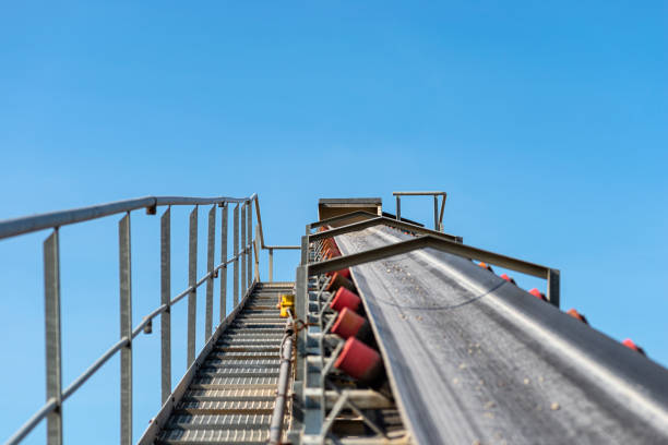 Close-up shot of the conveyor belt in the concrete plant with transport rollers, visible metal stairs and railings.